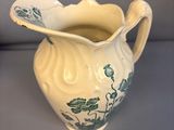 a white pitcher with blue flowers on it on a table