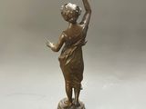 bronze figurine of a woman holding a bird on a pedestal
