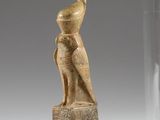 an egyptian carved statue of a woman under a glass clochet