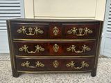 an antique chest of drawers with gold hardware on top of it