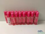 Neuf flacons de parfum rose sont alignés sur une surface blanche