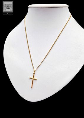 a gold necklace with a cross on a mannequin neck