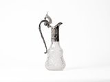 a glass pitcher with a metal handle on a white surface