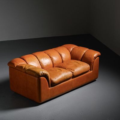 an image of a brown leather couch sitting in a dark room