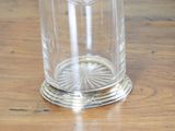 a glass vase on a wooden table with a flower in it
