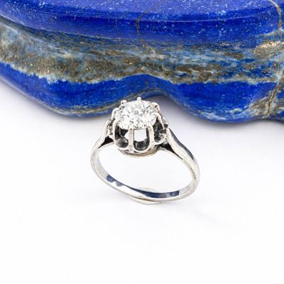 a close up of a diamond ring sitting on top of a blue stone