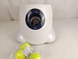 two tennis balls in a plastic bag next to a tennis ball dispenser