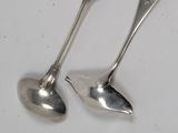 une paire de cuillères en argent posées sur une surface blanche