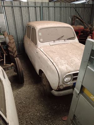 two old cars parked in a garage next to each other
