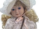 a doll that is wearing a white dress and a hat