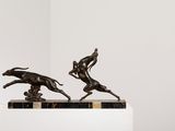sculpture of two running dogs on a marble base