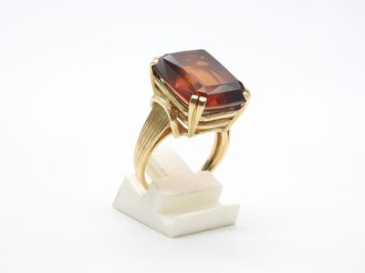 un gros plan d'une bague en or sertie d'une grosse pierre brune