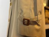 a beige coat with a brown belt on a mannequin mannequin