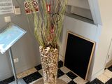 a tall vase with some plants in it on a black and white checkered floor