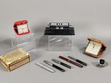 beaucoup de stylos, une horloge et une boîte posés sur une table
