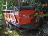 a boat that is sitting in the grass by some trees