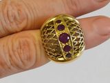 someone is holding a gold ring with a purple stone in it