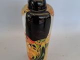 a black and yellow vase sitting on a white surface