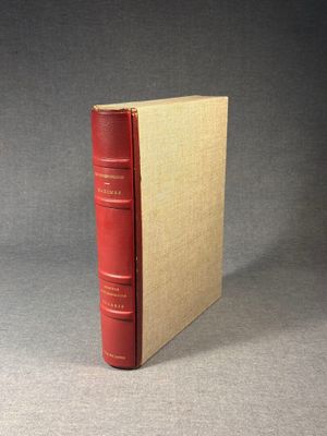 an old red book sitting on top of a table next to a gray wall