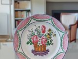 a plate with a basket of flowers on it on a table