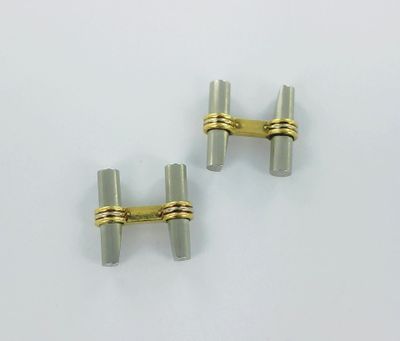 two silver and gold cufflinks with a gold clasp