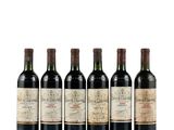 six bottles of wine are lined up on a white surface