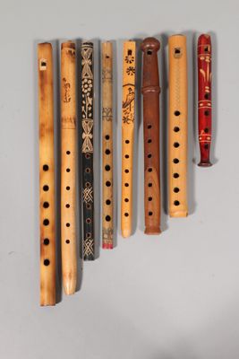 several wooden flutes are lined up against a white wall