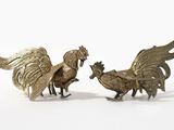 paire de figurines de coqs en laiton sur fond blanc