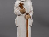 figurine of a monk holding a cross on a wooden base