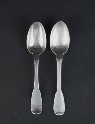 two silver spoons on a black surface with a black background