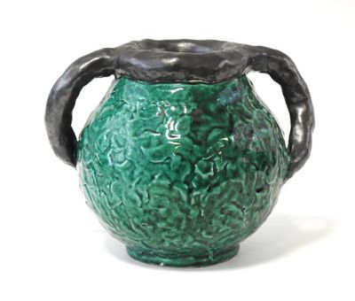 un vase vert avec une anse noire sur fond blanc