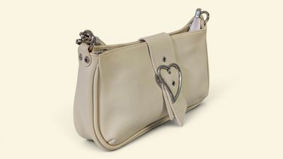 Le petit sac à main blanc est orné d'une boucle en forme de cœur sur le devant.