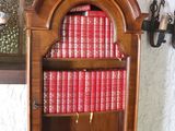a wooden bookcase with many red books on it
