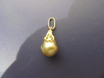 pendentif en perle jaune sur un fond noir, avec une ombre derrière