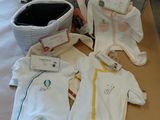 de nombreux vêtements de bébé étalés sur une table dans une pièce