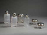 plusieurs bouteilles en verre avec des bouchons argentés, posées sur une surface blanche