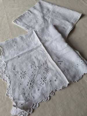 two white napkins on a bed with white sheets