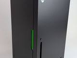 a close up of a black xbox game console with a green handle
