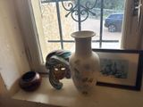 a white vase sitting on a window sill next to a picture