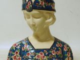 une figurine en céramique représentant une femme coiffée d'un chapeau