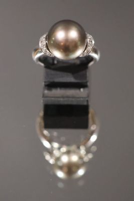 gros plan d'une bague en perles et diamants sur une surface noire
