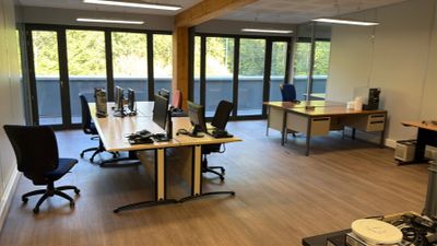 Il y a de nombreux bureaux et chaises dans ce bureau qui donne sur l'extérieur.