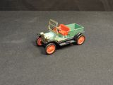 a green toy car with orange wheels on a black surface