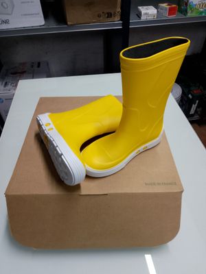 une botte en caoutchouc jaune posée sur une boîte, elle-même posée sur une table