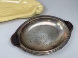 a silver plate with a bird on it next to a yellow bowl