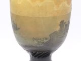 a yellow vase sitting on a black stand on a white surface