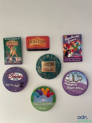 many different disney buttons on a white wall