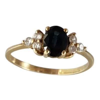 un gros plan d'une bague en or sertie d'une pierre noire et de diamants blancs