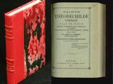 un vieux livre posé sur une table noire, à côté d'un livre rouge