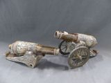 paire de canons anciens plaqués argent, munis de roues en bois, sur fond gris